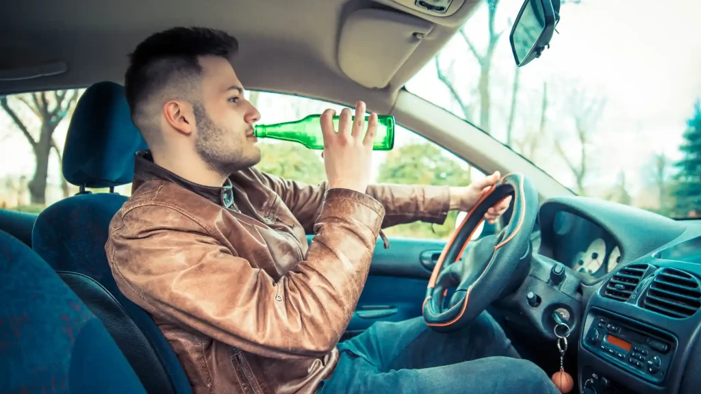 Man drinking beer while driving a car