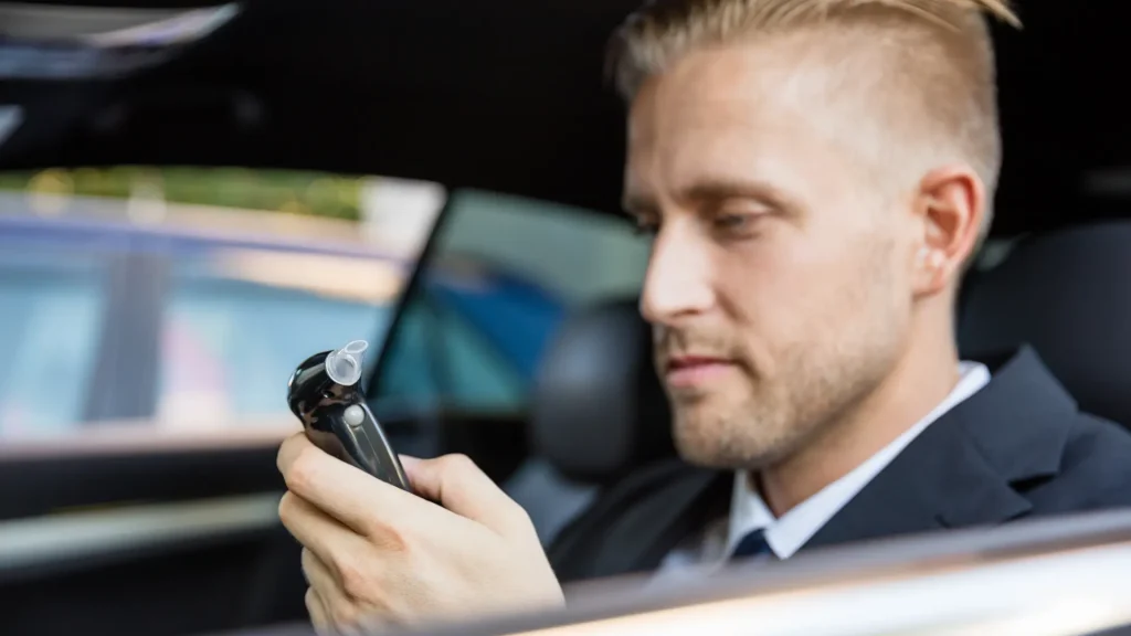 Man in car holding breathalyzer